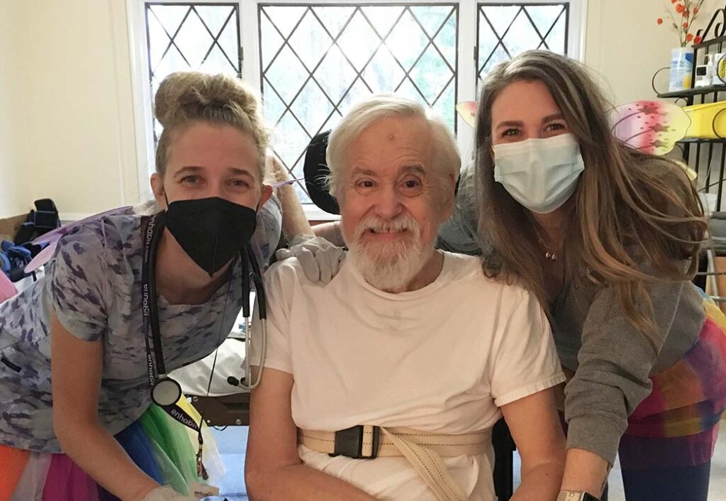 Home health patient Paul smiles with his physical therapist Kaitlin and occupational therapist Stephanie