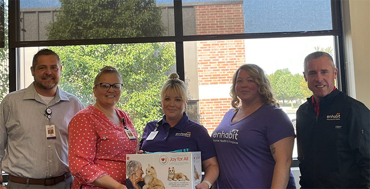 The Enhabit team smiles together with the boxed AI therapy cat
